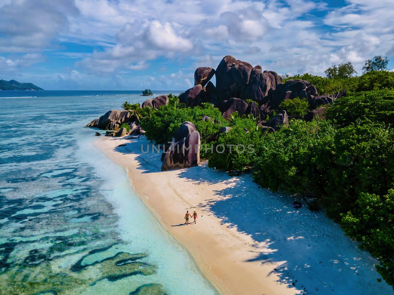 Anse Source d'Argent beach, La Digue Island, Seychelles, couple men and woman walking at the beach during sunset at a luxury vacation