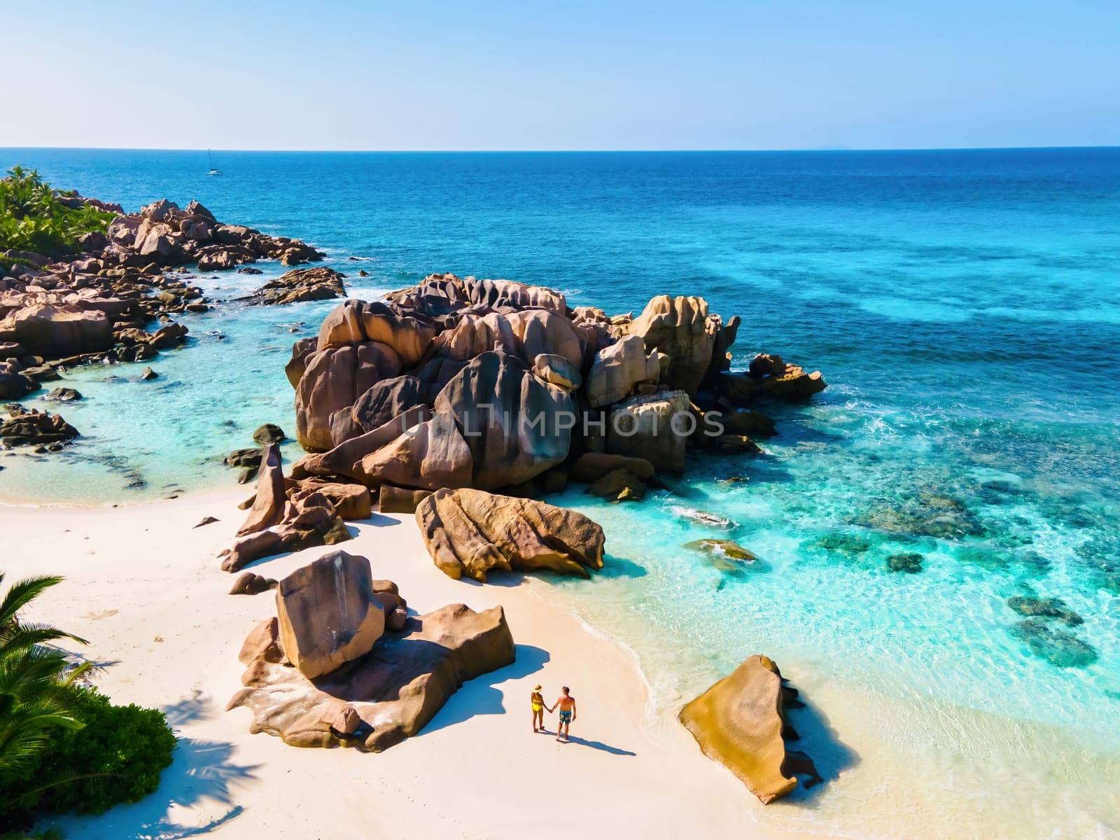 Anse Cocos beach, La Digue Island, Seychelles, Drone aerial view of La Digue Seychelles bird eye view. of tropical Island, couple men and woman walking at the beach during a luxury vacation