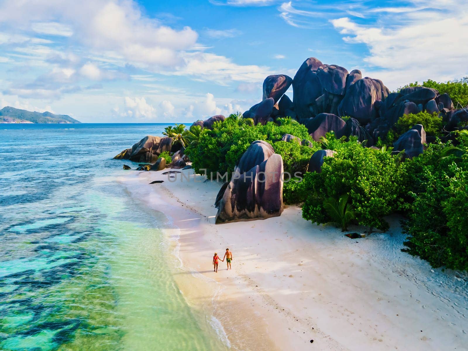 Anse Source d'Argent beach, La Digue Island, Seychelles, Drone aerial view of La Digue Seychelles, couple men and woman walking at the beach during sunset at a luxury vacation