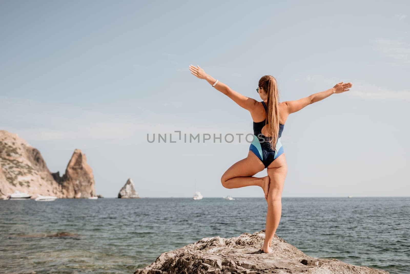 Woman sea yoga. Happy woman meditating in yoga pose on the beach, ocean and rock mountains. Motivation and inspirational fit and exercising. Healthy lifestyle outdoors in nature, fitness concept. by panophotograph