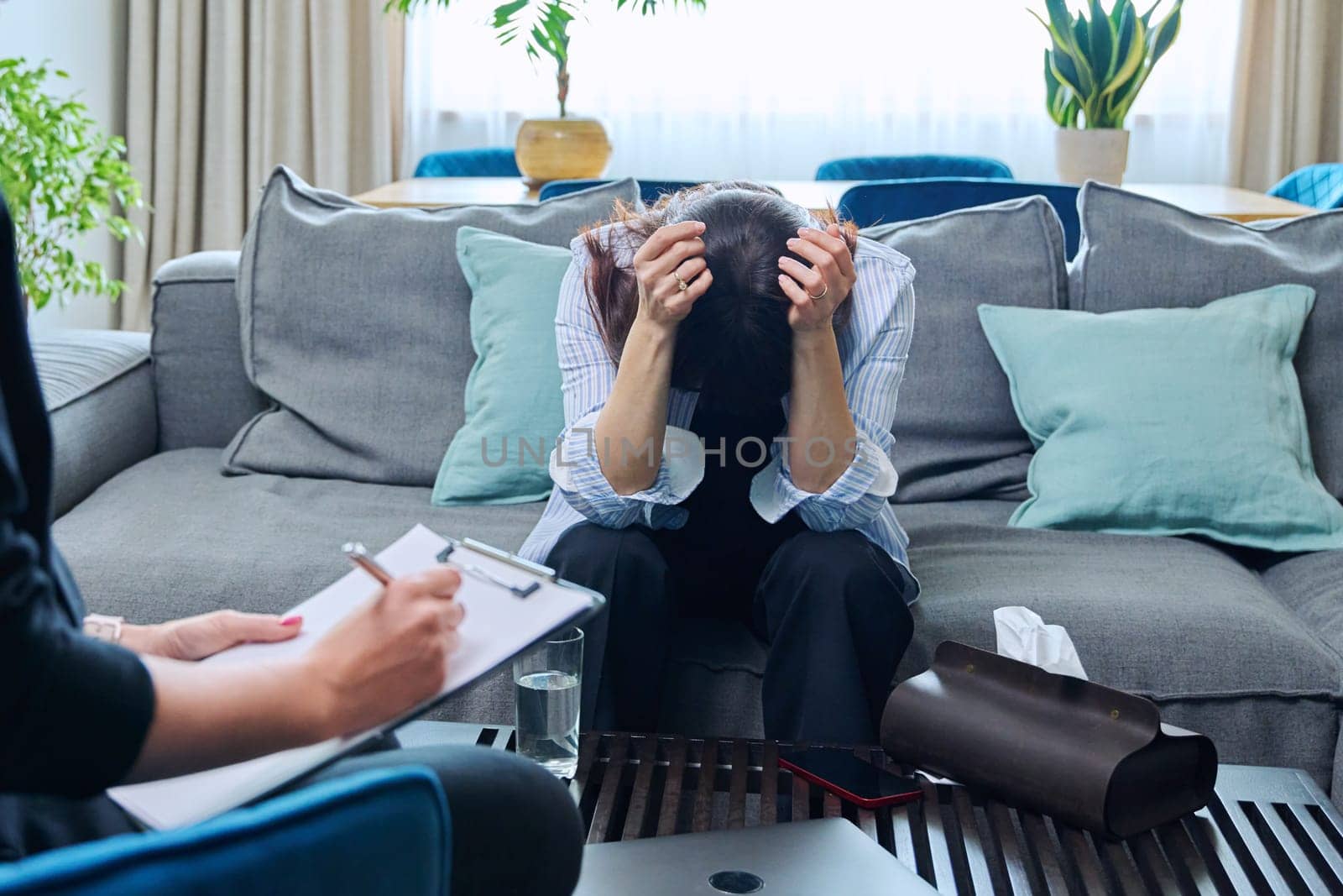 Sad upset crying middle-aged woman sitting on couch in therapy with psychologist counselor therapist. Psychology, psychotherapy, mental health, professional support, treatment, mature people concept