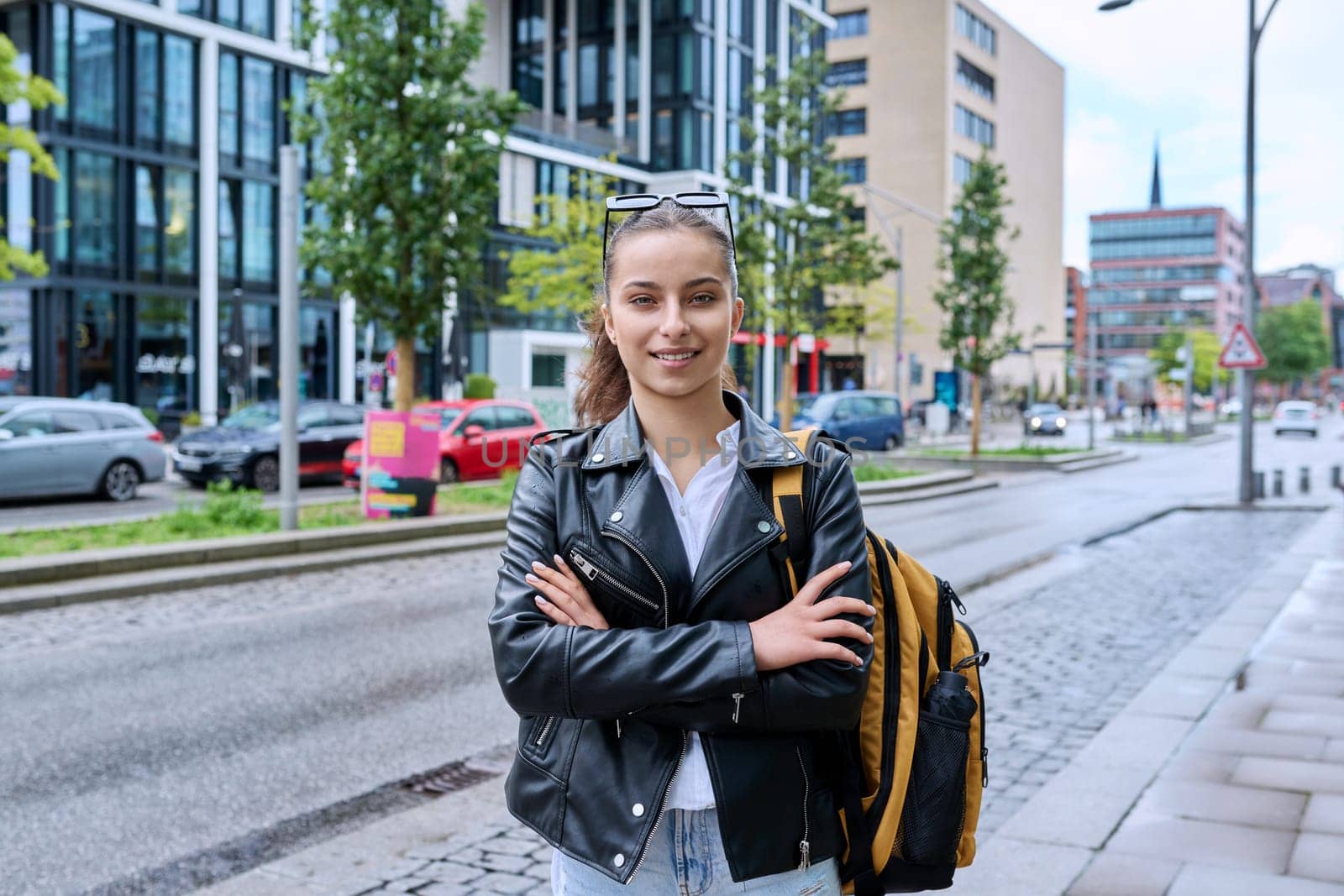 Portrait of teenage high school student girl with backpack on city street by VH-studio