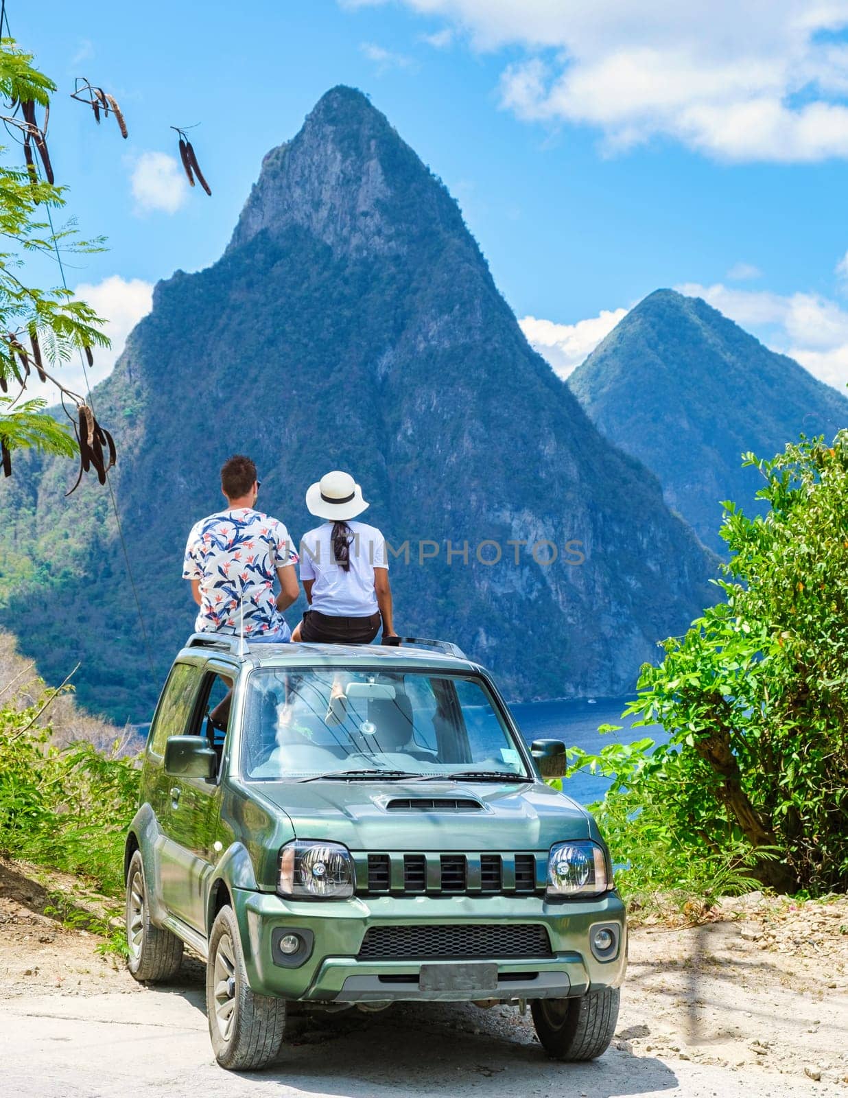 a couple of men and women exploring the Island of St Lucia in a rental car. Mountains of Saint Lucia with in the background the huge pitons of Saint Lucia Caribbean Island