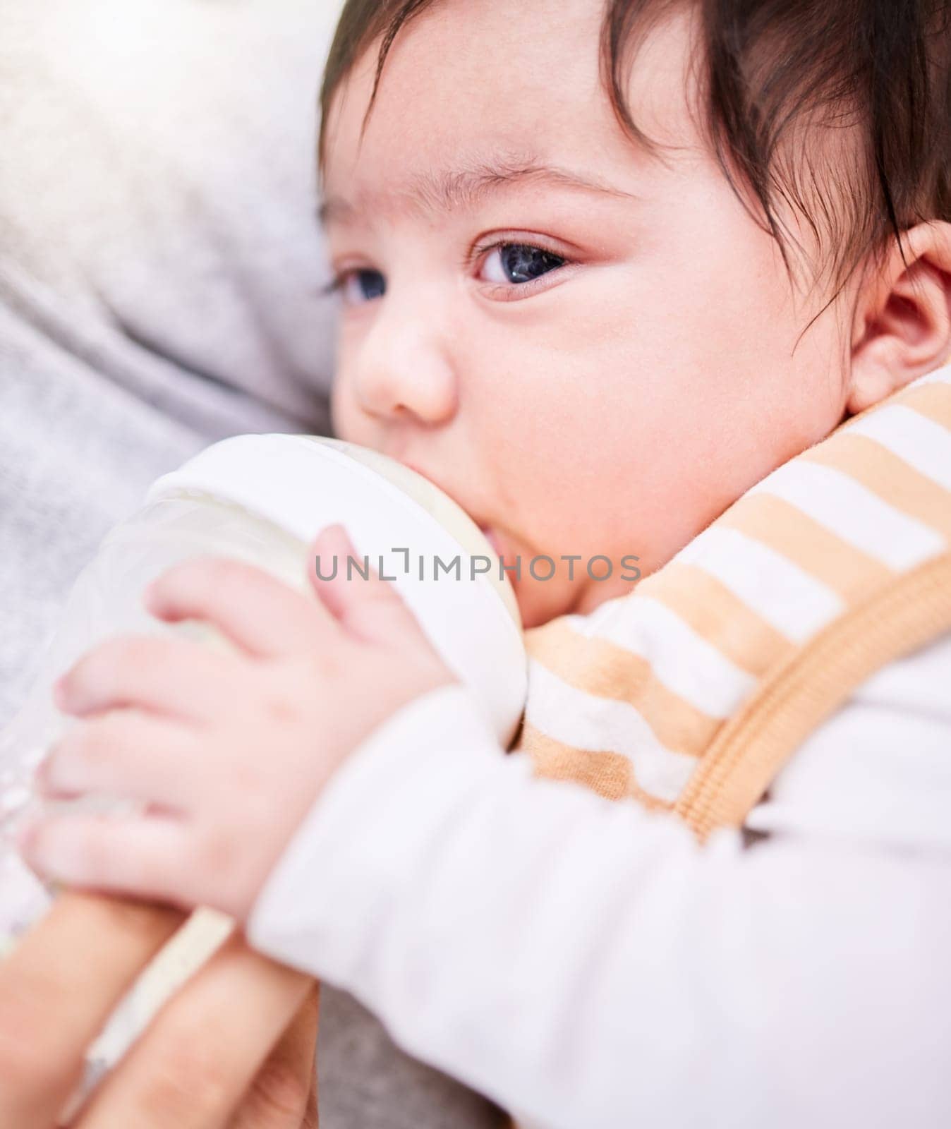 Face, milk and a baby drinking from a bottle closeup with a parent for health, diet or nutrition. Food, formula or calcium and an adult feeding a hungry infant child for growth and development.