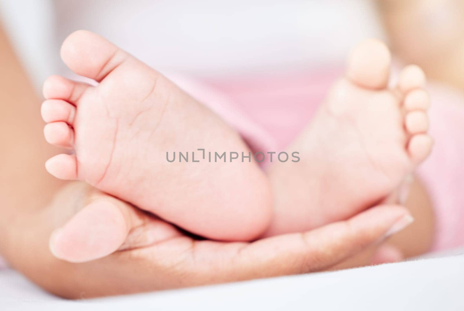 Family, care and the feet of a baby in the hands of a parent closeup in the bedroom of their home together. Kids, love or wellness and an infant child on a bed in an apartment with an adult person.