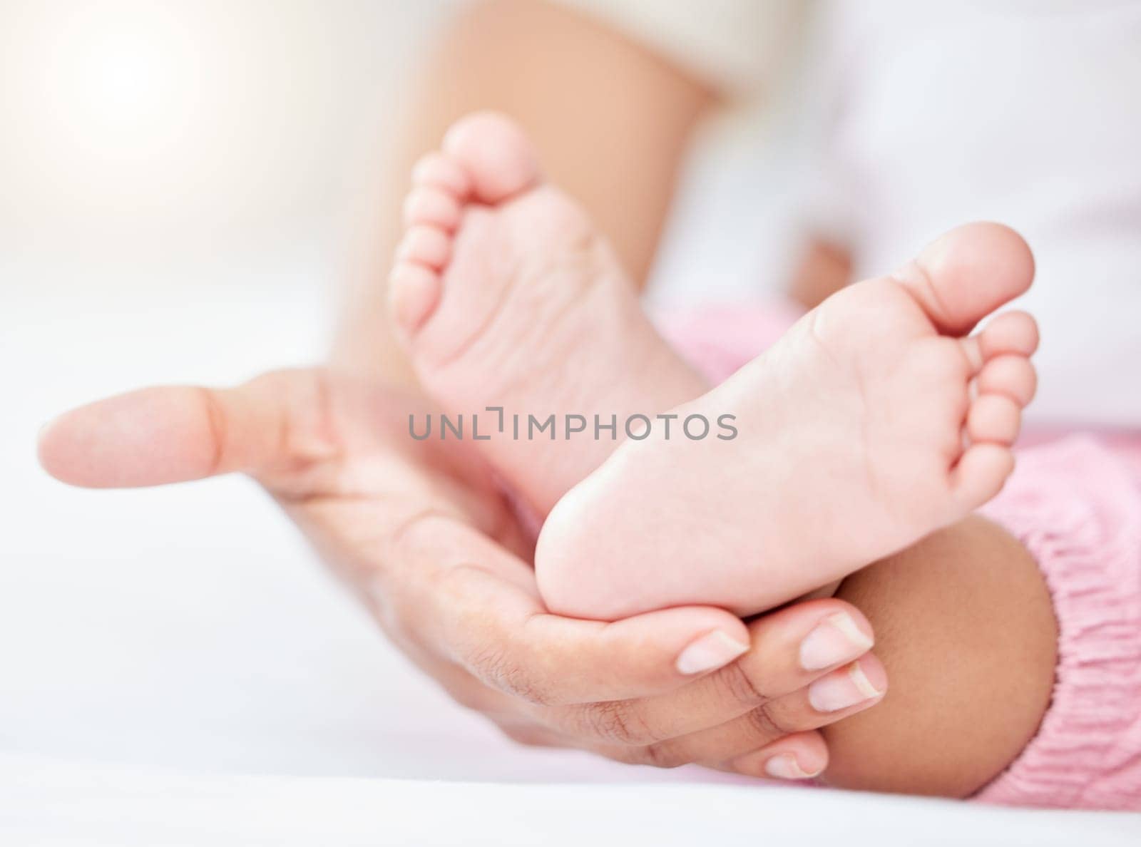 Family, love and the feet of a baby in the hands of a parent closeup in the bedroom of their home together. Kids, care or wellness and an infant child on a bed in an apartment with an adult person.