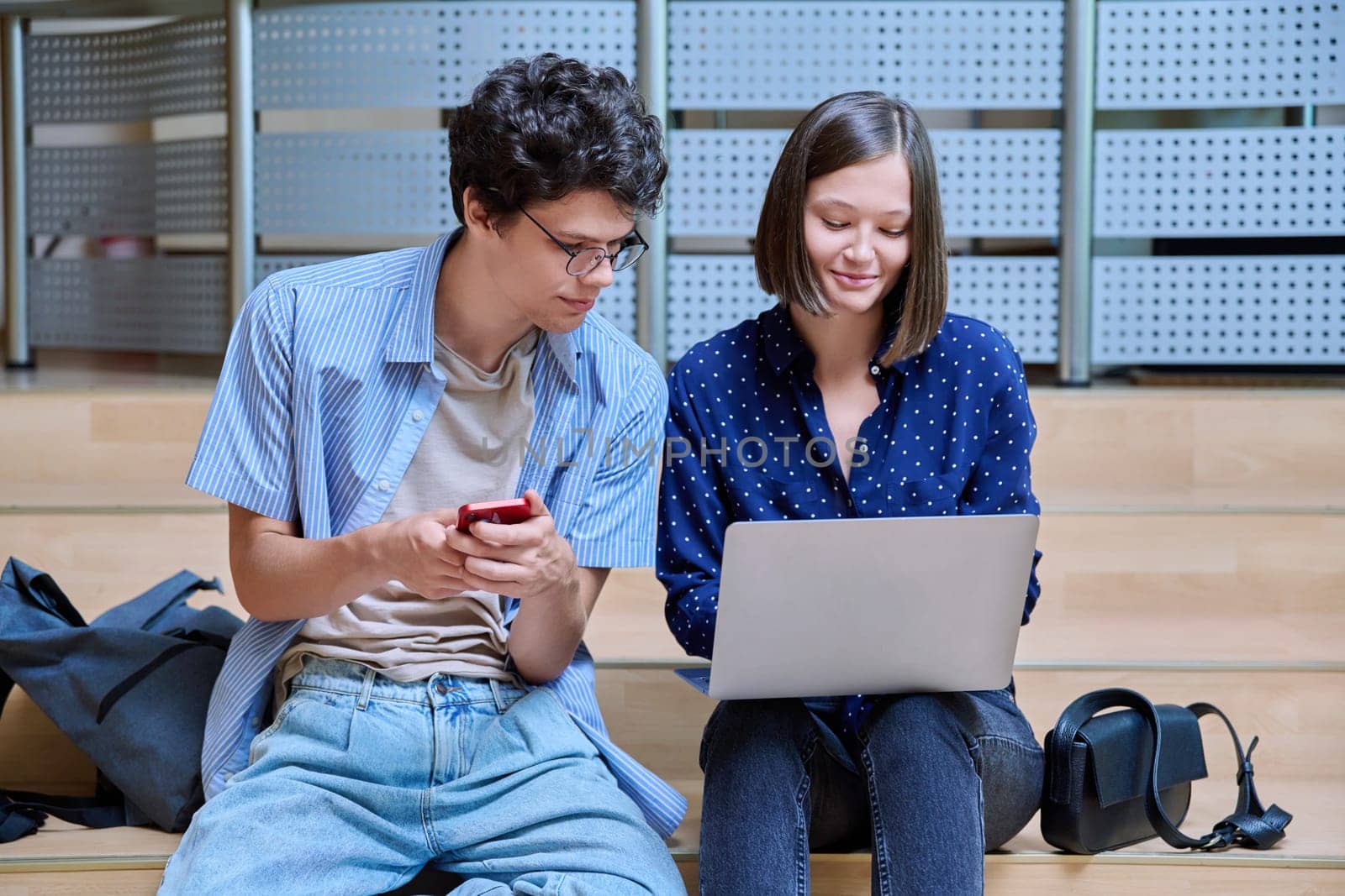Friends classmates college students guy and girl with smartphone laptop inside educational building. Youth, lifestyle, technology, mobile applications for learning leisure communication