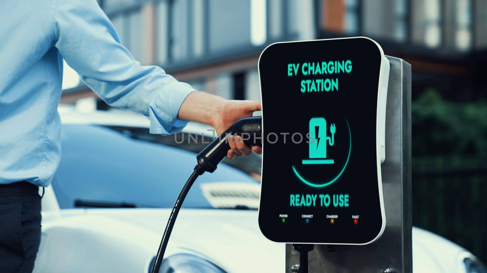 Businessman recharge his electric car from charging station. Peruse by biancoblue