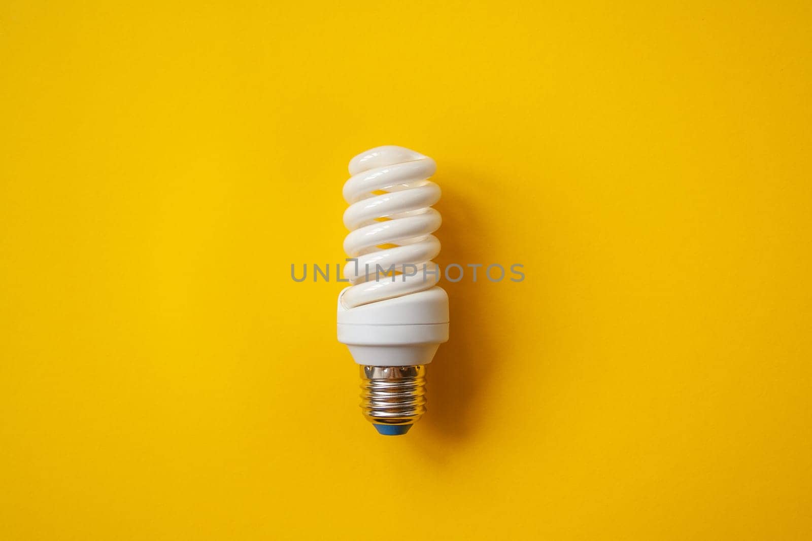 Energy saving light bulb on a orange background. Economical consumption of electricity. The concept of nature conservation