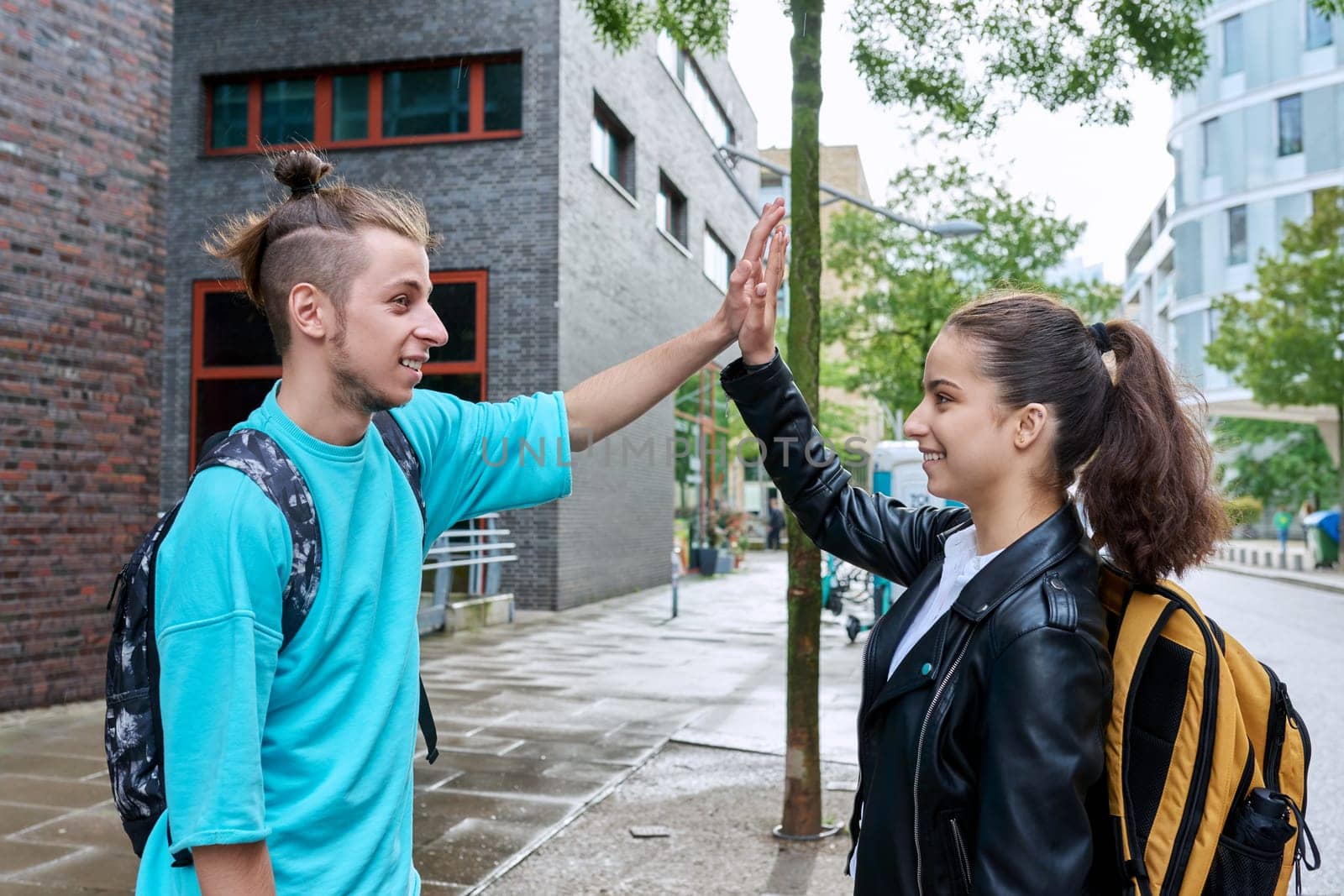 Teenage friends meeting outdoor, guy and girl with backpacks, teenagers high school students shake hands. Youth, adolescence, communication, leisure, friendship lifestyle concept