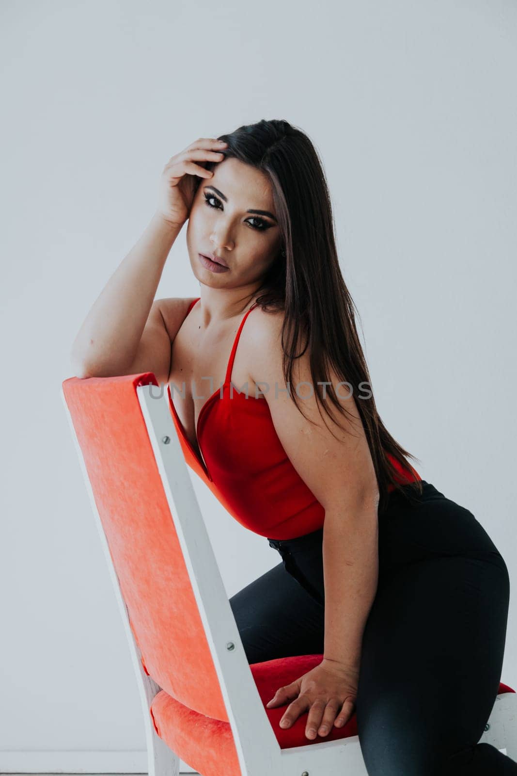 Brunette posing near a chair on a white