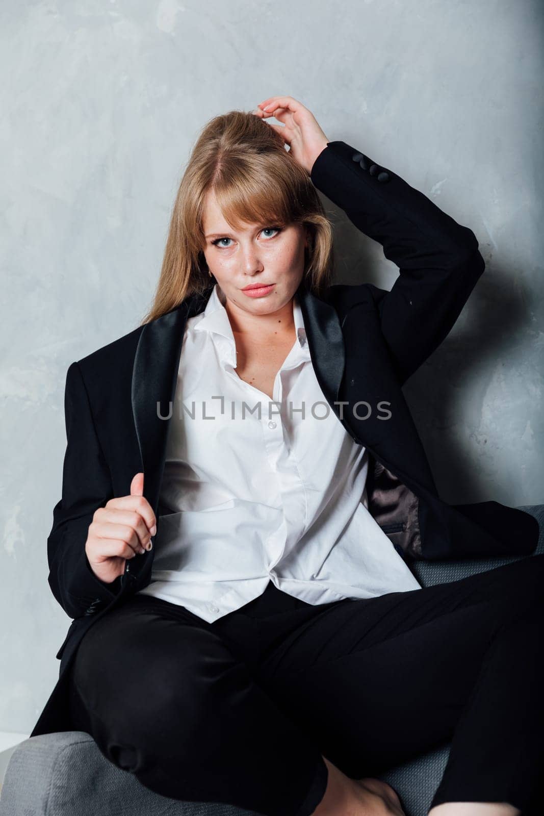 Business red-haired woman posing on gray armchair by Simakov