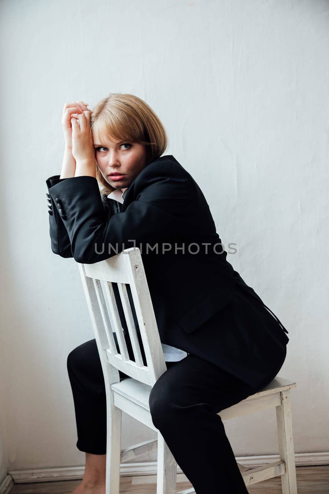 red-haired woman posing by white chair