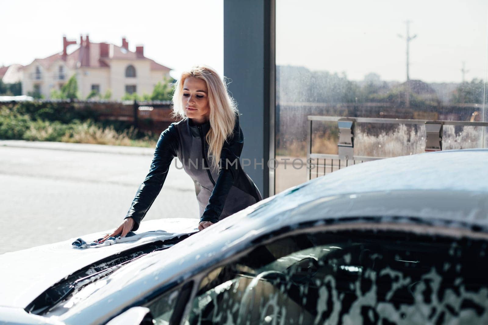 Beautiful woman washing car at car wash dry cleaning by Simakov