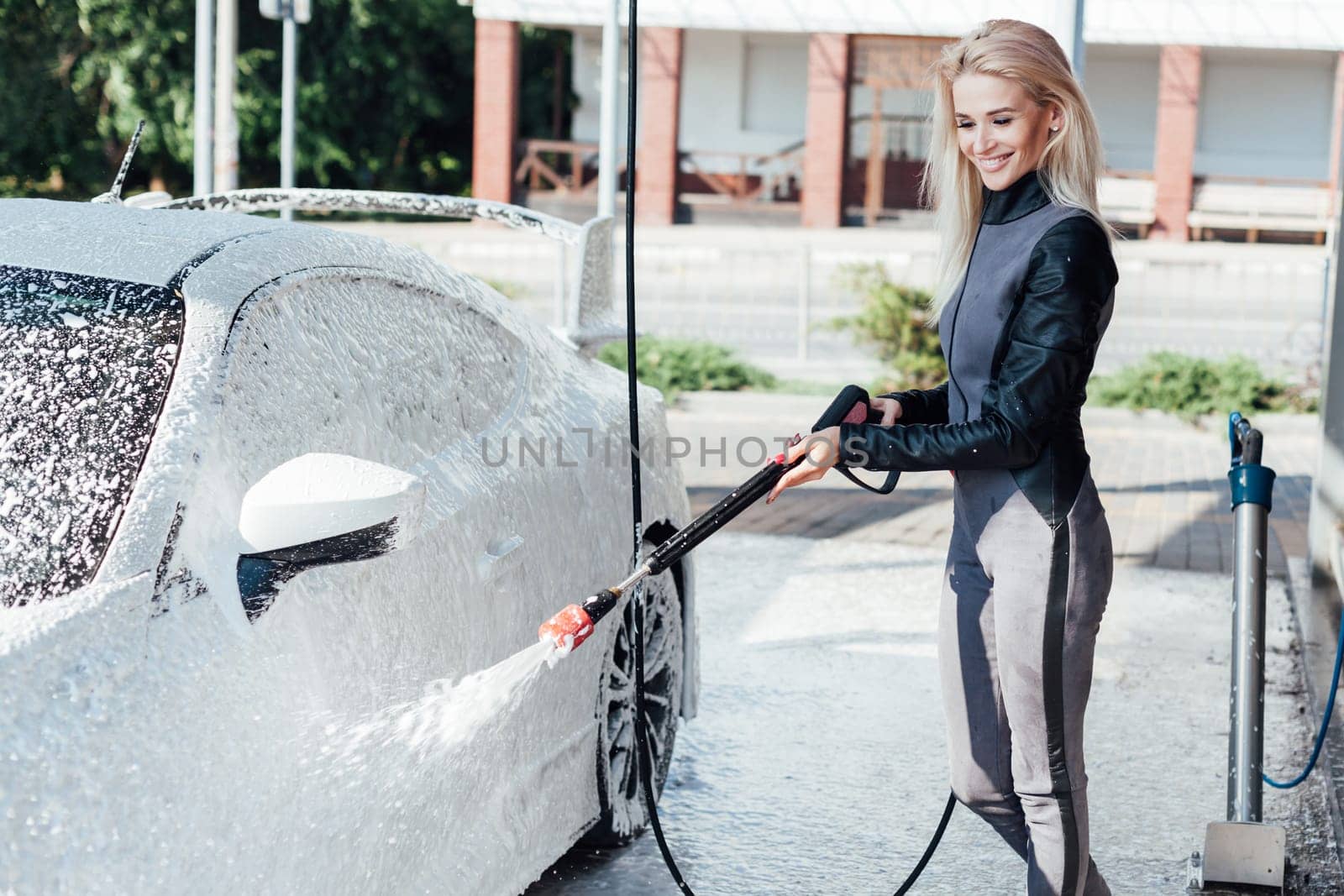 Beautiful woman washing car at car wash dry cleaning by Simakov