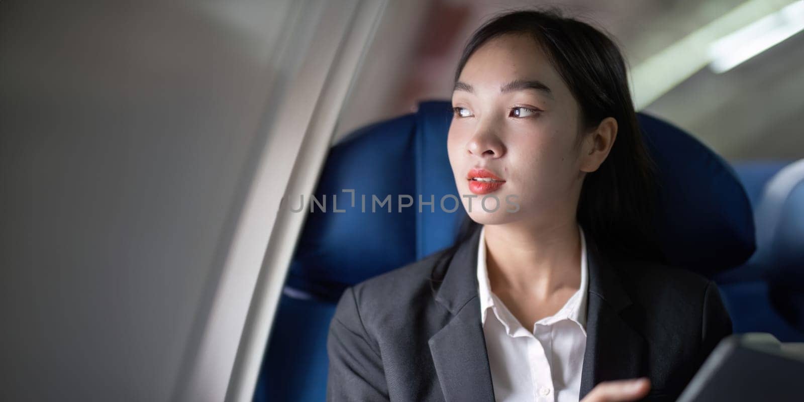 Successful Asian business woman, Business woman working in airplane cabin during flight on tablet.