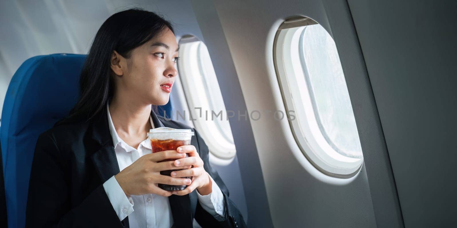 Successful Asian business woman, Business woman working in airplane on laptop computer and looking out the window.