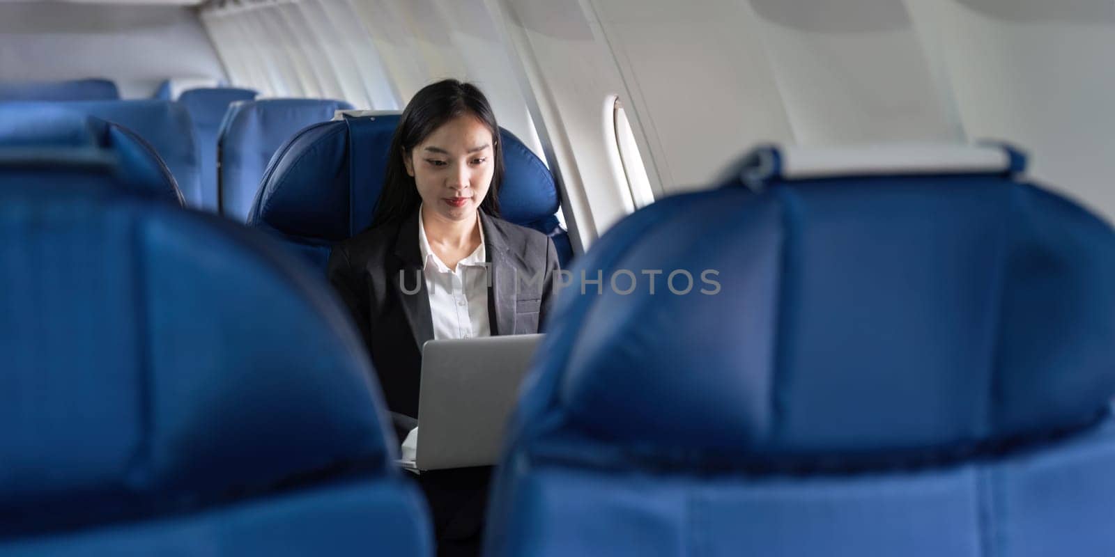 Successful Asian business woman, Business woman working in airplane cabin during flight on laptop computer.