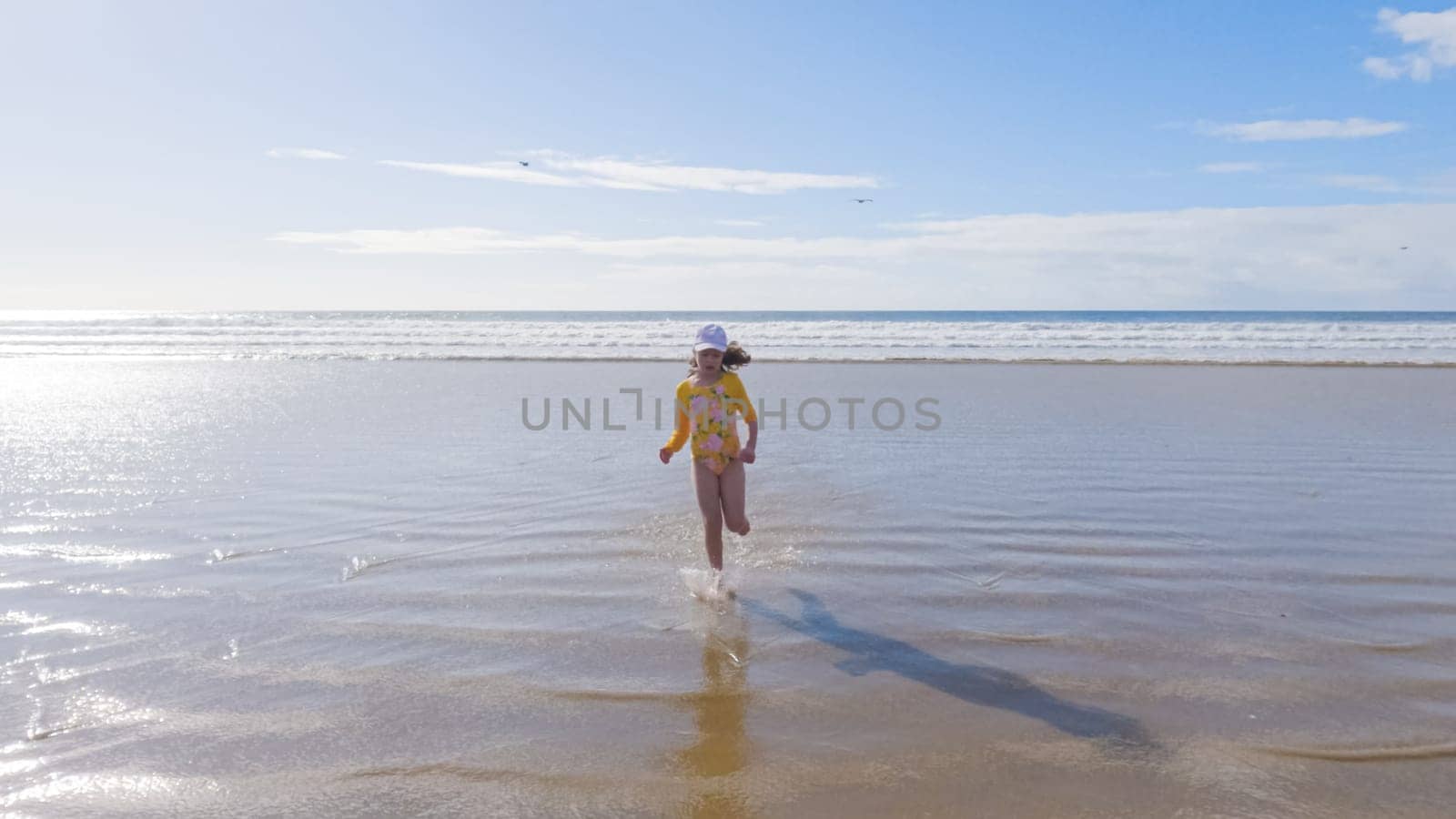 Little Girl Joyfully Running on Winter Beach by arinahabich