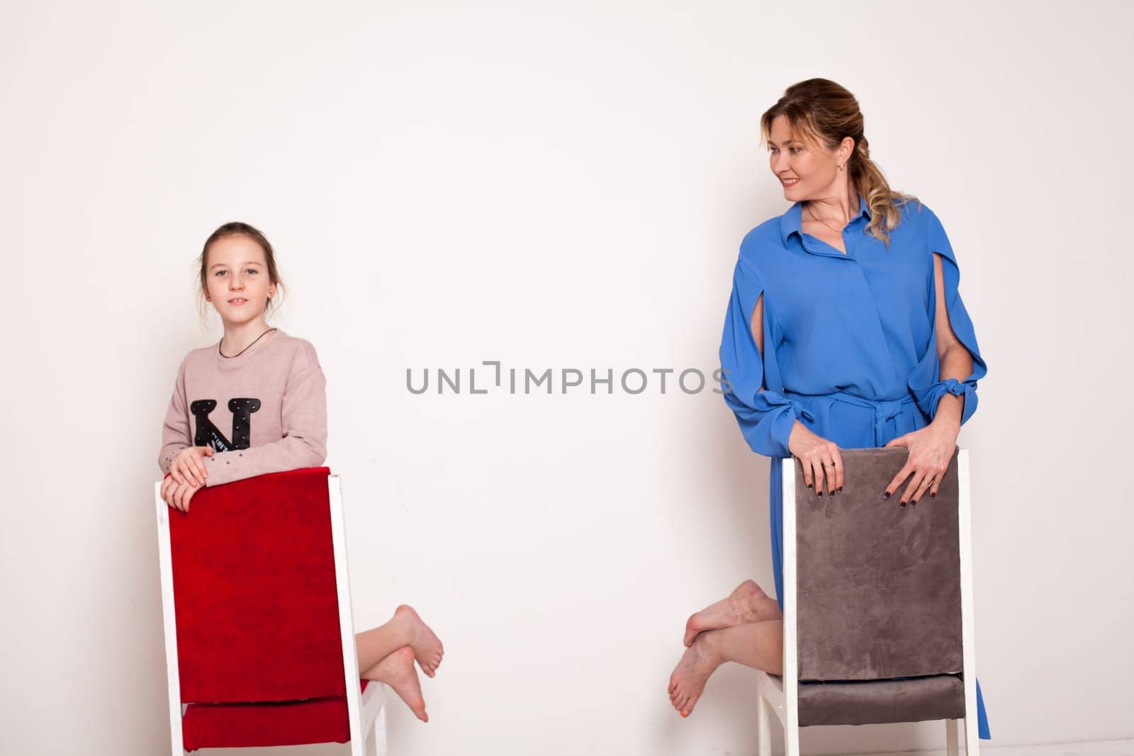 Mom and daughter posing near chairs Family