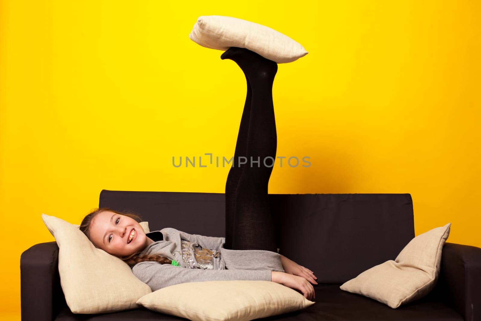 Cheerful girl lying on the couch with pillows by Simakov