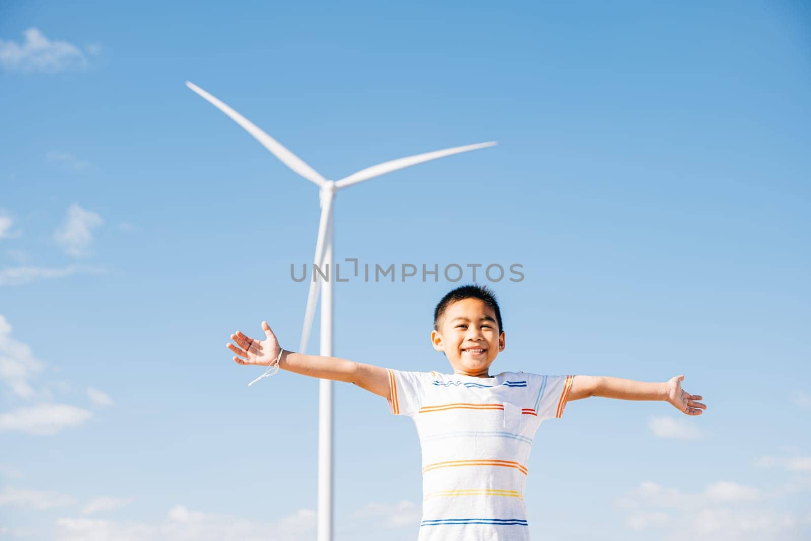 A happy boy in a wind farm's environment. Family joy and carefree moments near turbines celebrating nature's escape and clean energy. The child's smiling face amid windmill technology.
