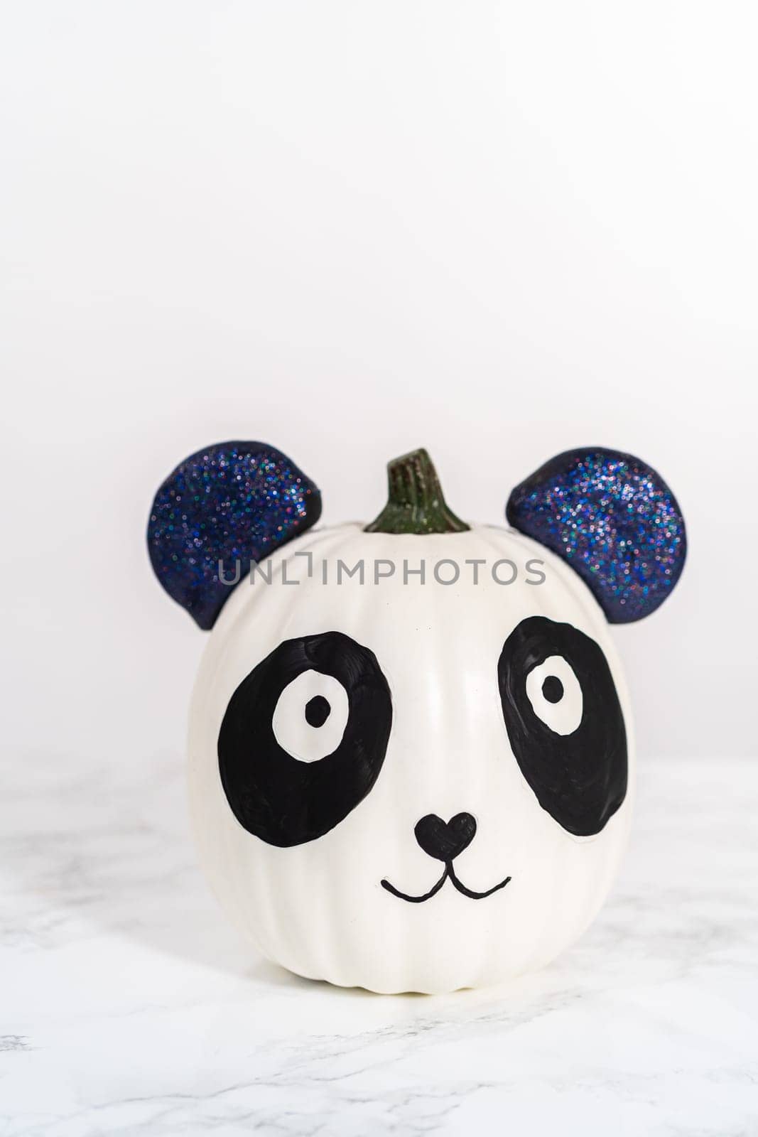 Panda pumpkin with glittery ears for Halloween on a white background.