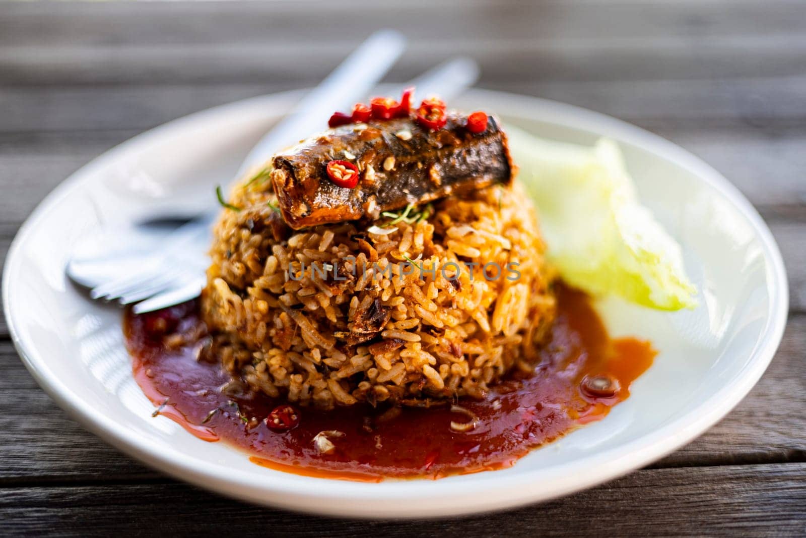 Fried Rice with Canned Mackerel in white dish on a wooden table. Thai style fusion food.