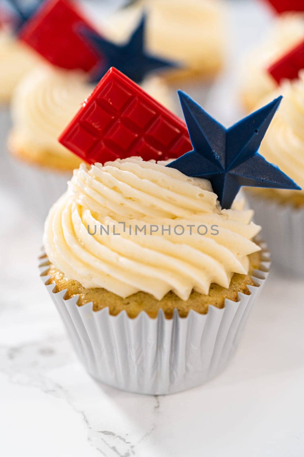 Lemon cupcakes with lemon buttercream frosting, and decorated with patriotic blue chocolate star and red mini chocolate.