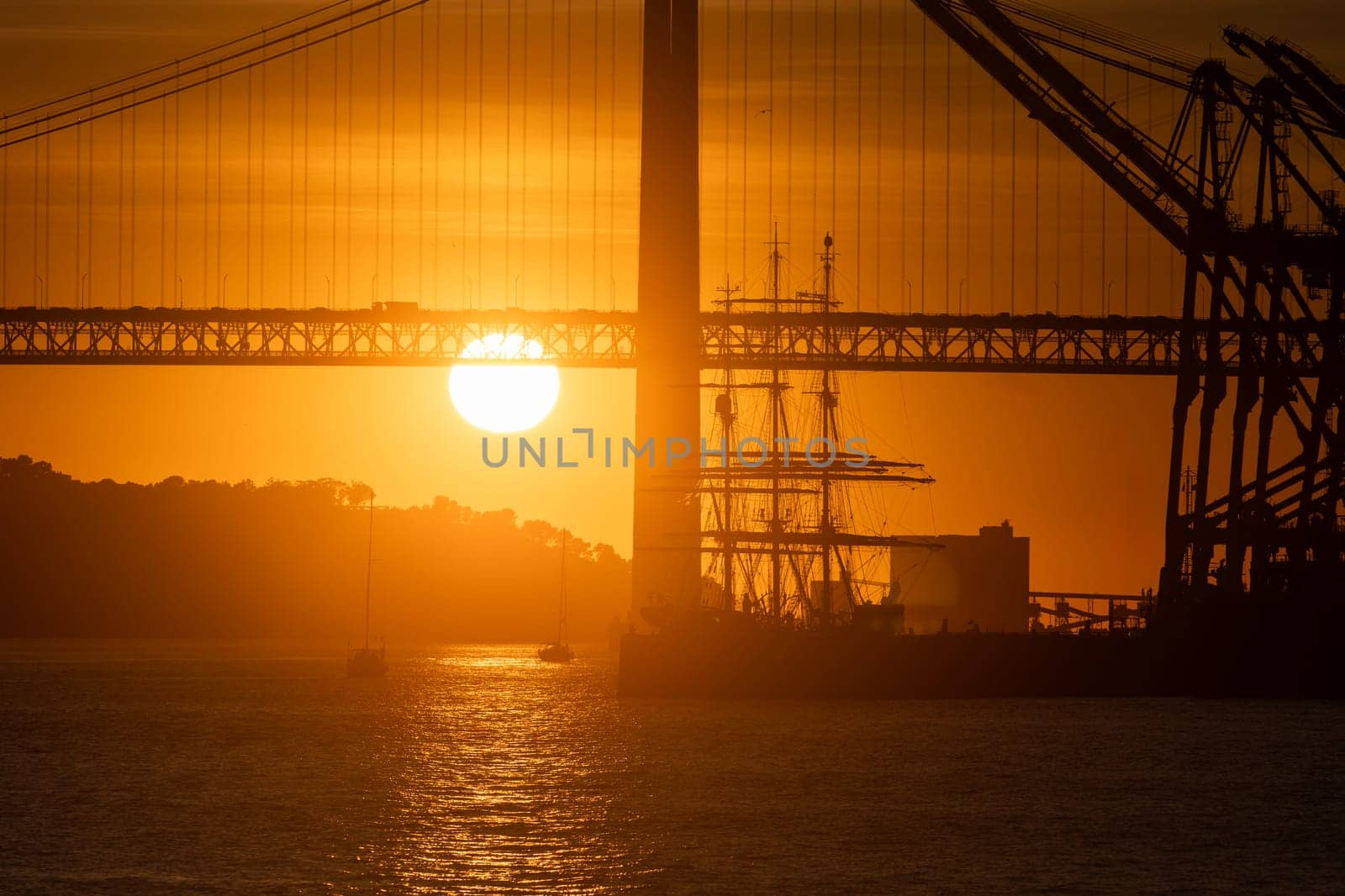 The sun is setting behind a bridge over water