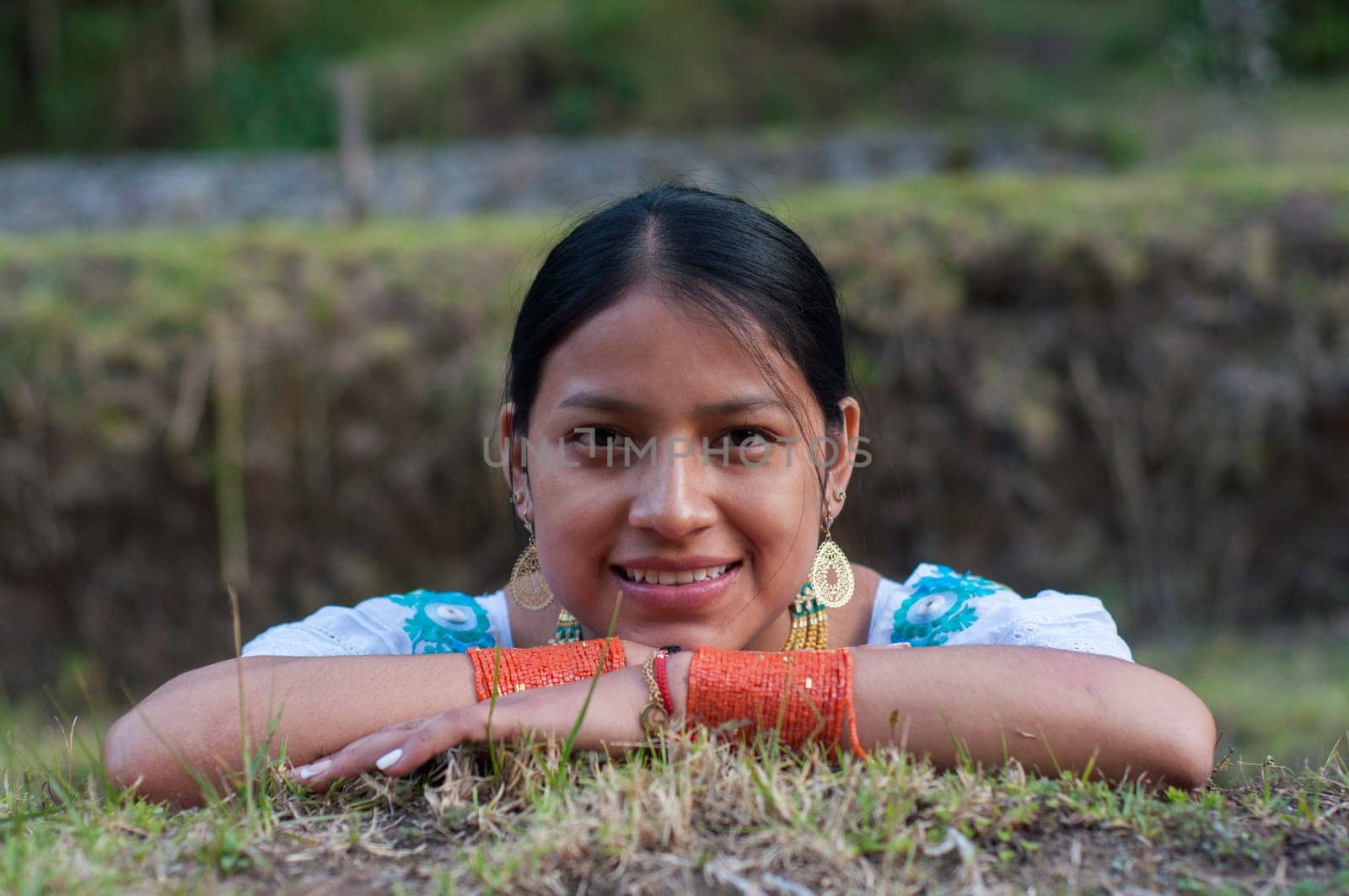 closeup of native girl from otavalo-ecuador lying on the grass looking at camera and smiling. High quality photo
