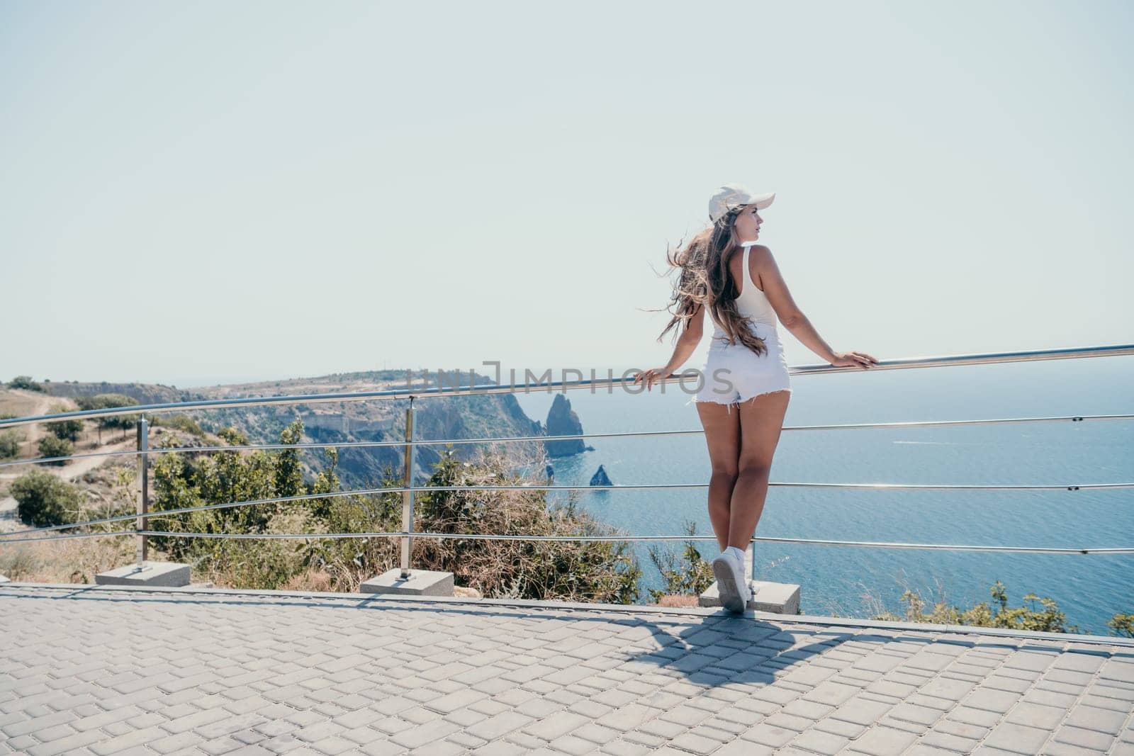 Woman summer travel sea. Happy tourist enjoy taking picture outdoors for memories. Woman traveler posing over sea bay surrounded by volcanic mountains, sharing travel adventure journey by panophotograph