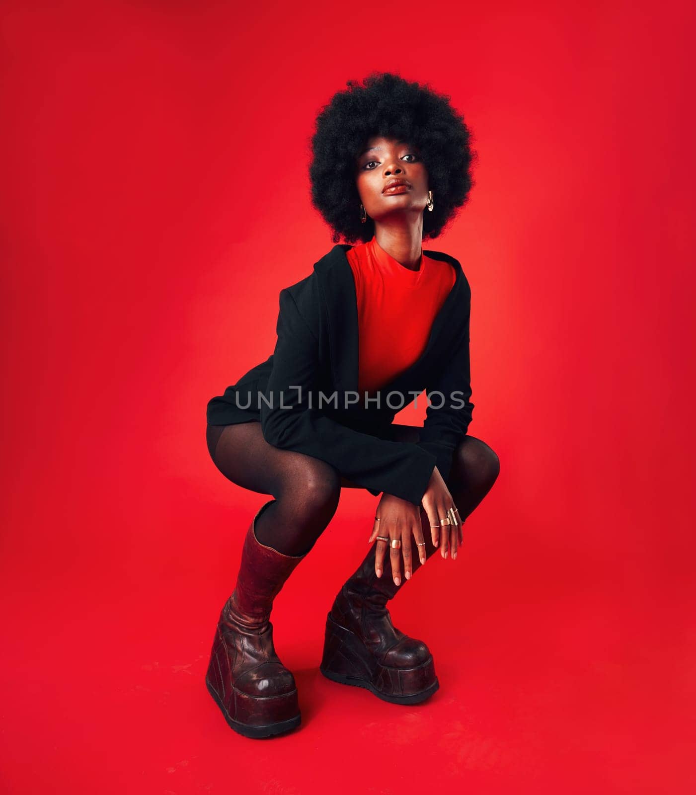 Black woman, makeup and afro, hair and fashion in portrait with shine isolated on red background. Hairstyle, haircare and texture with growth, stylish clothes and confident African model in a studio by YuriArcurs