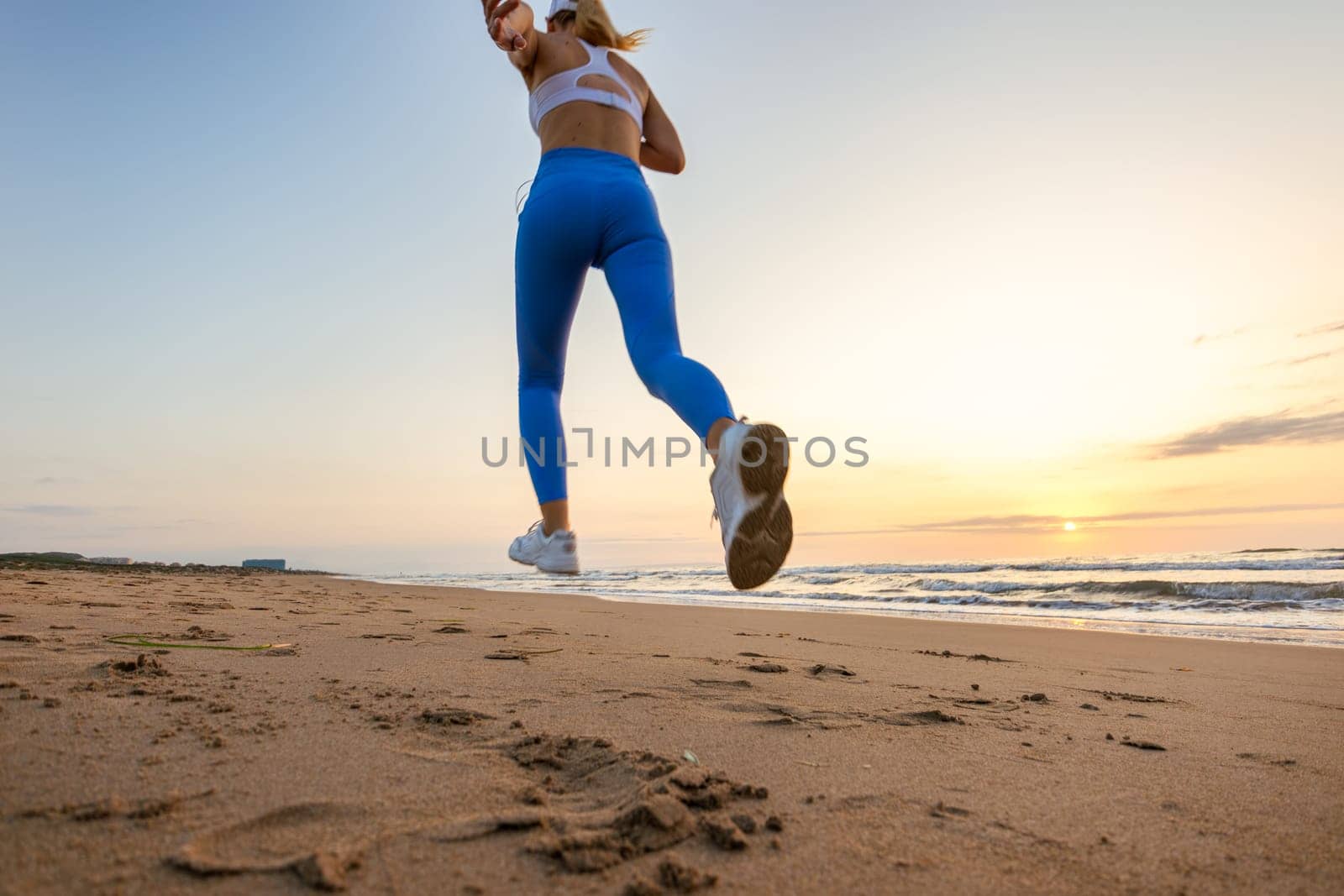 sportive woman running along beautiful sandy beach, healthy lifestyle, enjoying active summer vacation near the sea. High quality photo