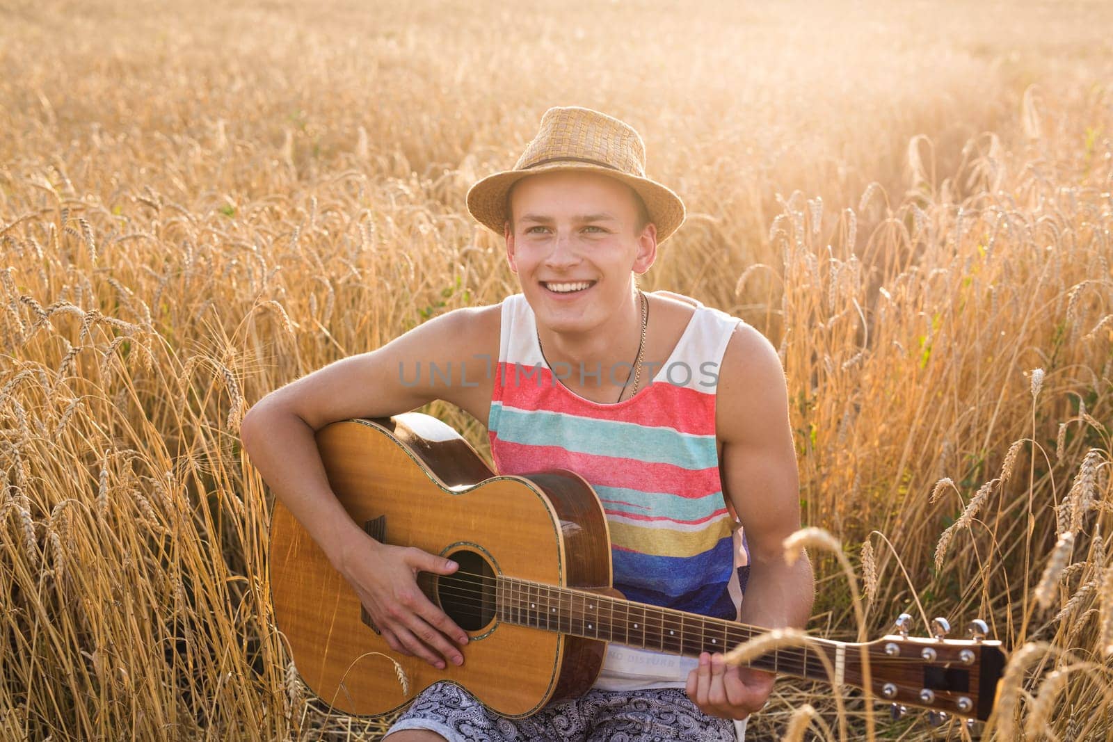 Cheerful traveling musician with his guitar outside in a wheat field. by Satura86