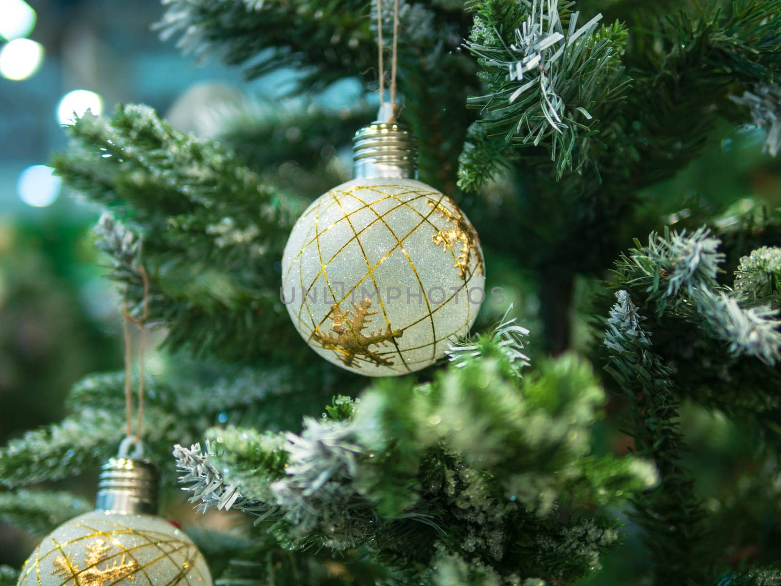 artificial christmas tree with white and golden ball ornament. defocused background