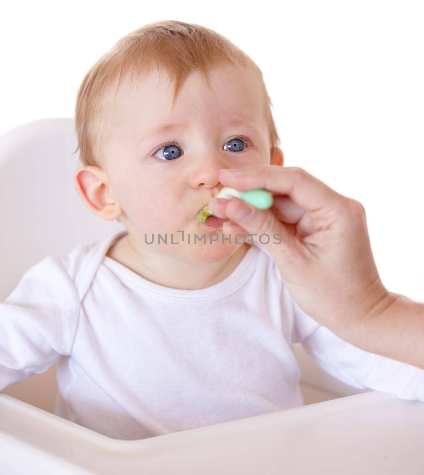 Cute, spoon and baby eating vegetables in feeding chair in a studio for health and nutrition. Sweet, natural and boy newborn, child or kid enjoying a meal for wellness diet by white background
