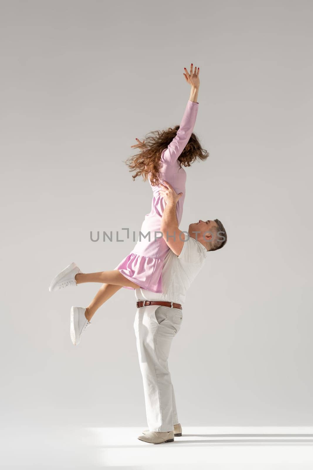 Beautiful young couple dancing on light background. by AnatoliiFoto