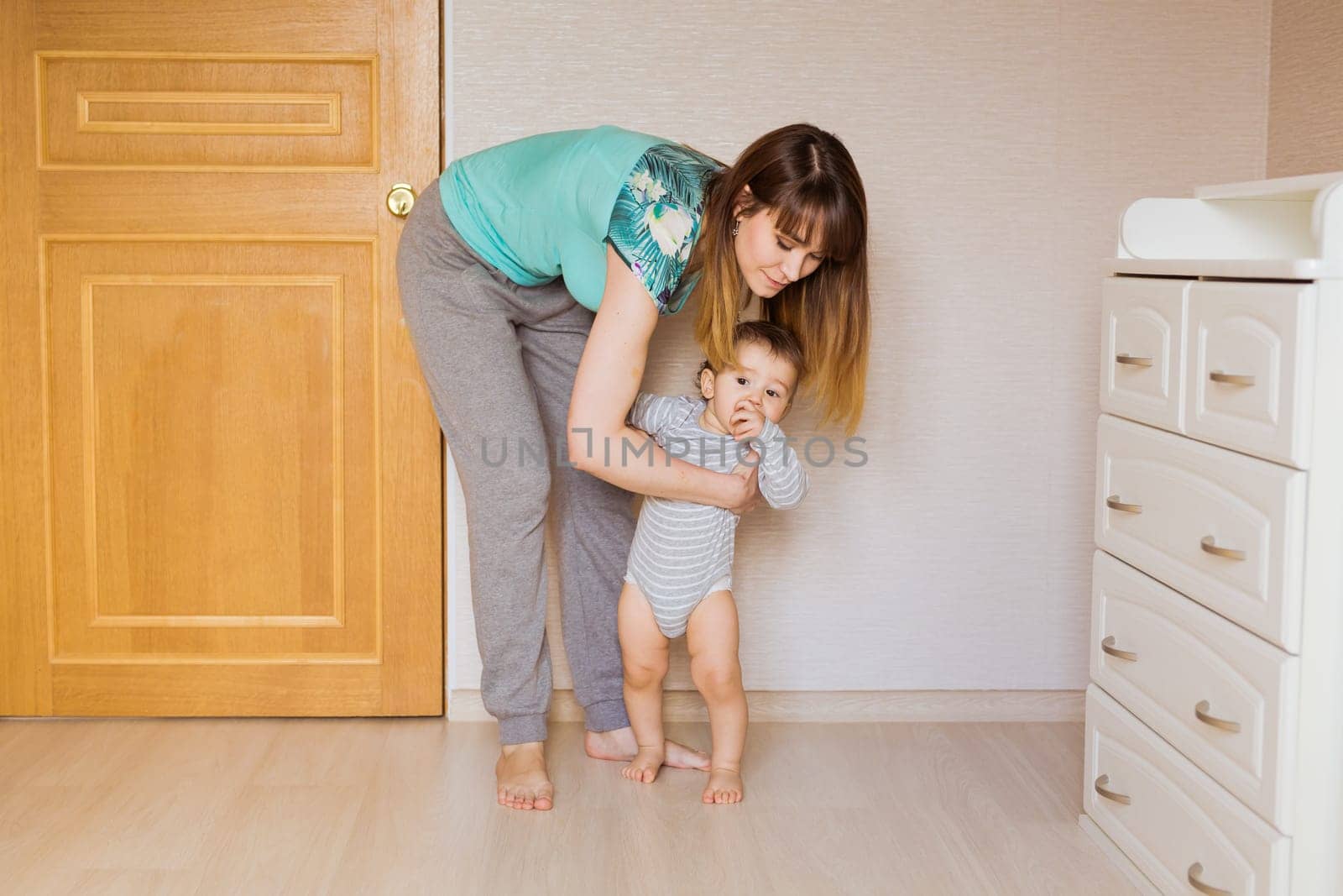 little boy first steps with the help of mom.