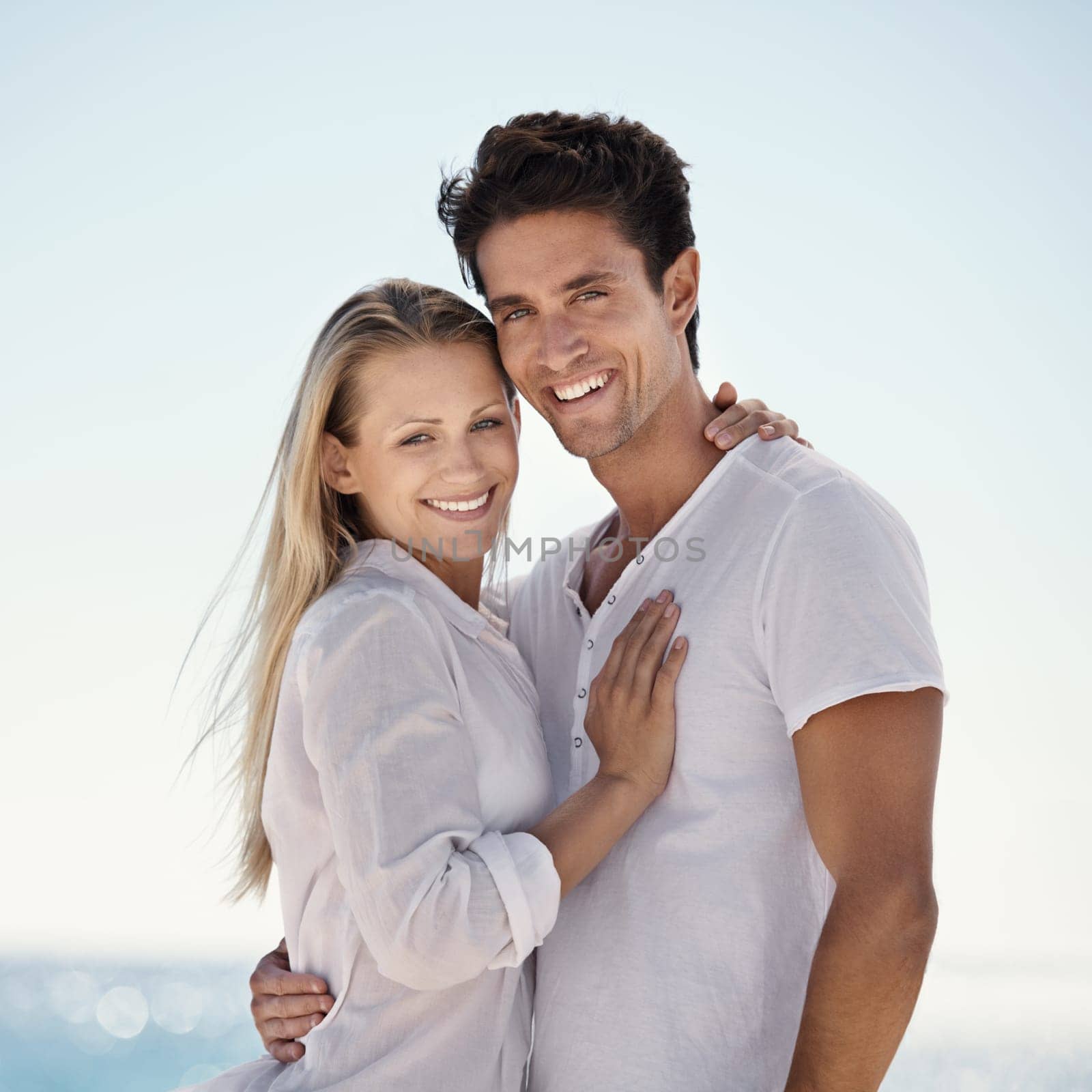 Couple, beach portrait and hug with love, support and care on a date by the sea with romance on vacation. Holiday, ocean and outdoor with summer travel in nature relax on a break and trip by water.