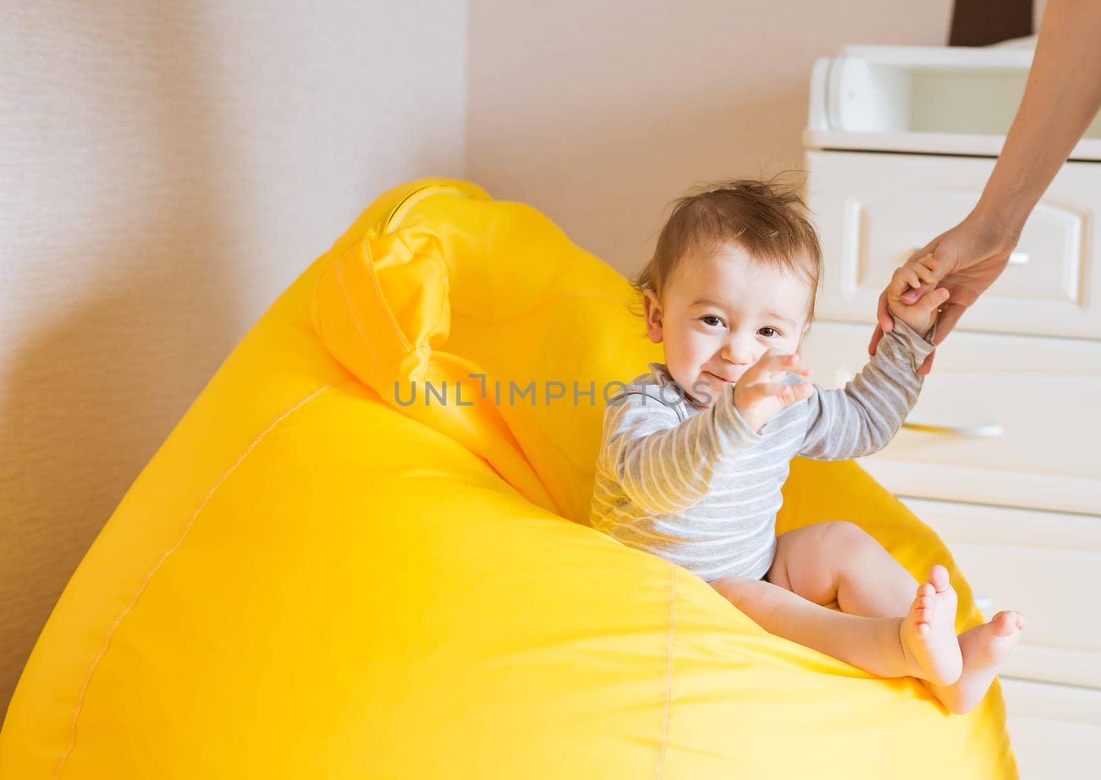 Beautiful adorable laughing baby boy infant face. Smiling child sits on a chair