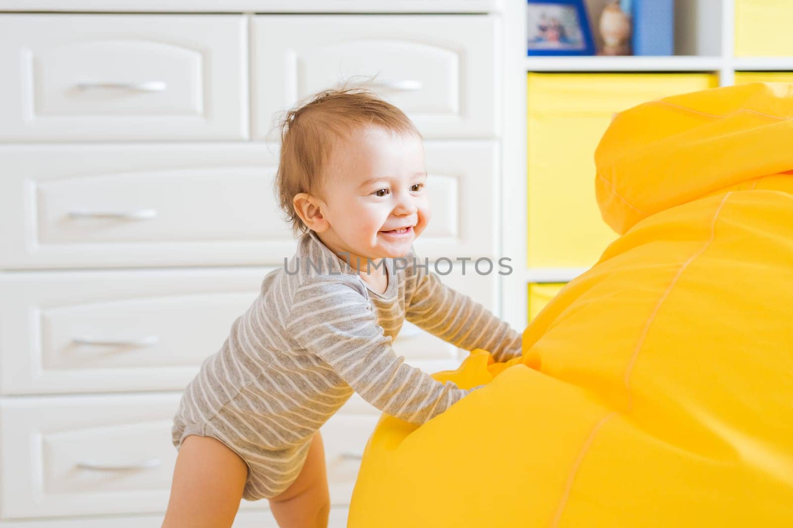 Beautiful adorable laughing baby boy infant face. Smiling child sits on a chair