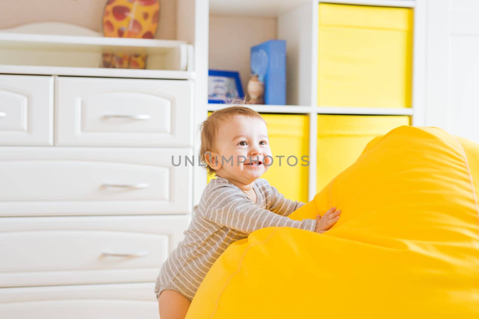 Beautiful adorable laughing baby boy infant face. Smiling child sits on a chair