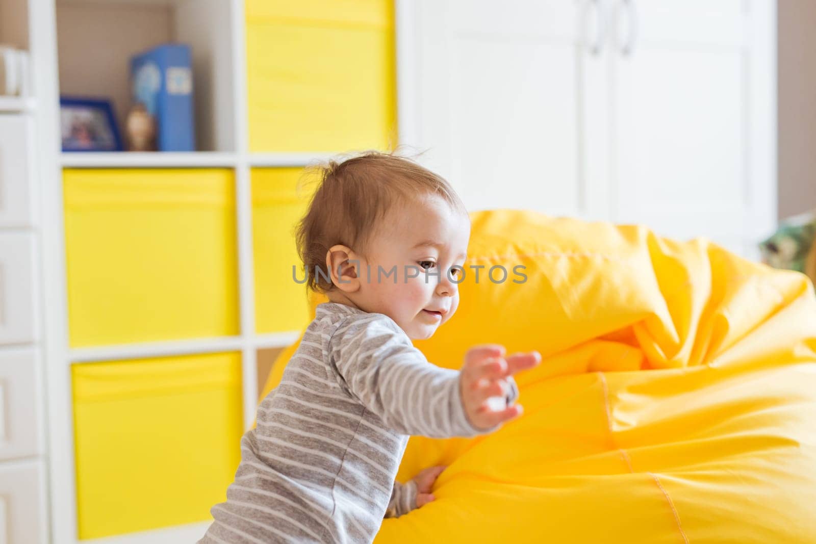 Beautiful adorable laughing baby boy infant face. Smiling child sits on a chair