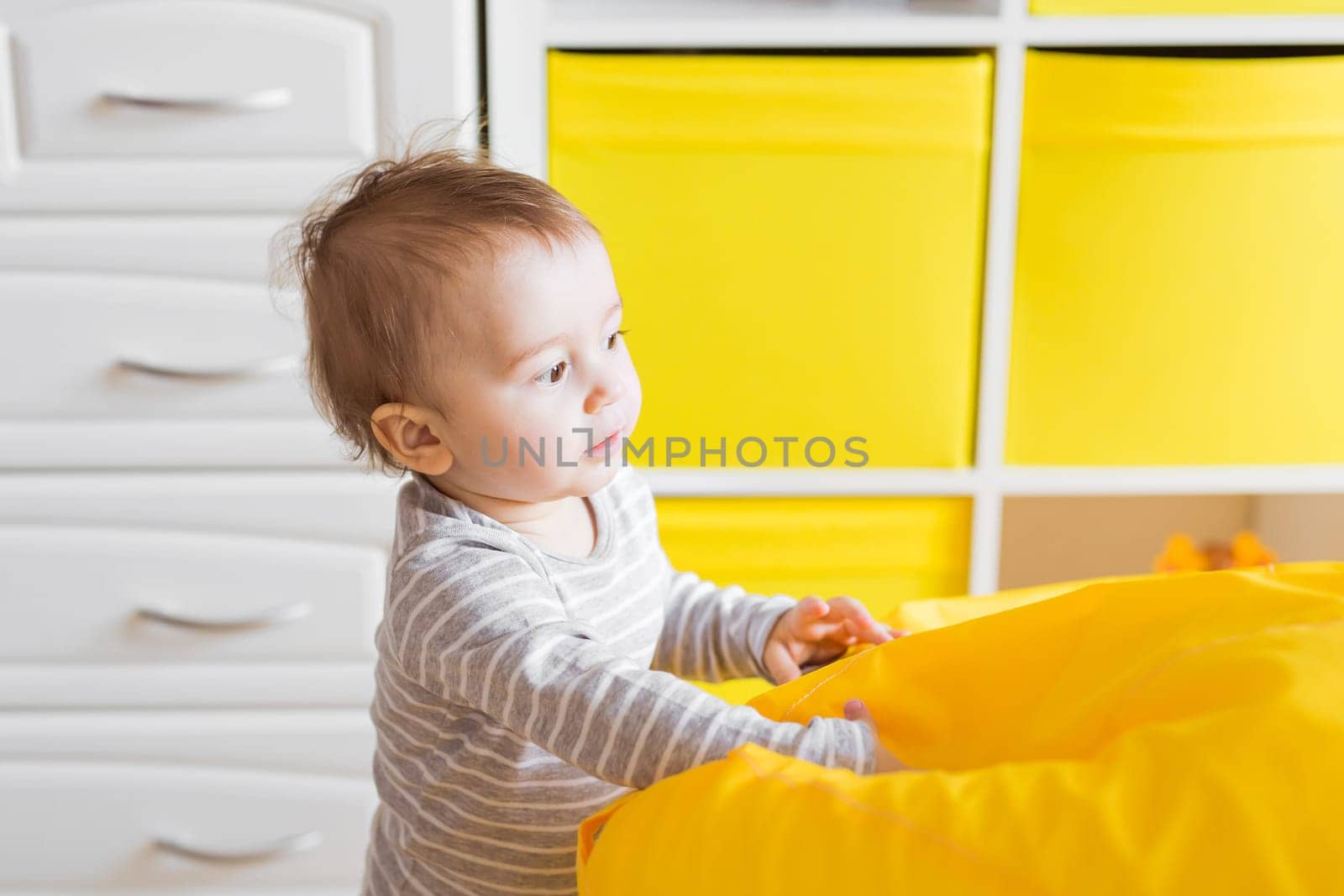 Beautiful adorable laughing baby boy infant face. Smiling child sits on a chair