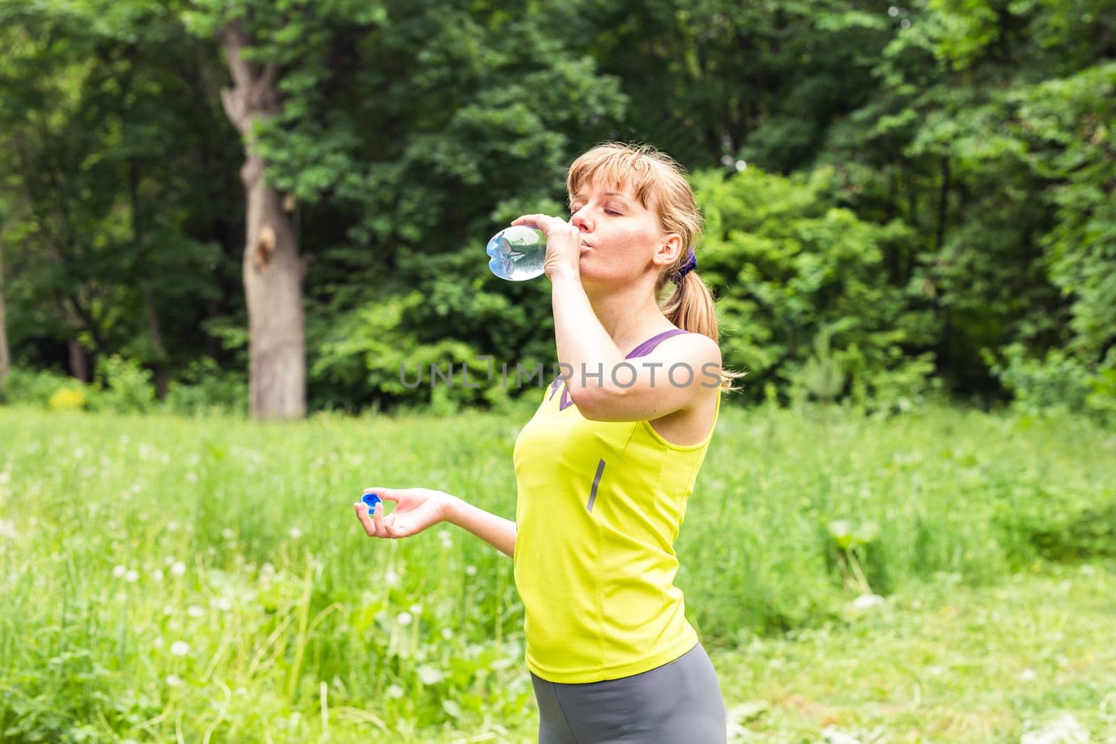 Fitness woman drinking water from bottle. by Satura86