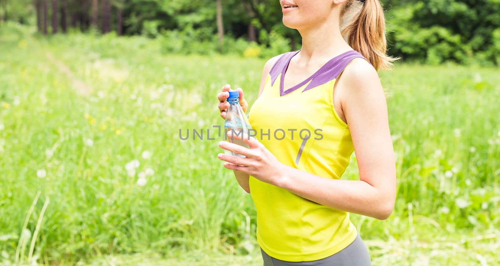 Fit woman outdoors holding a bottle of water.