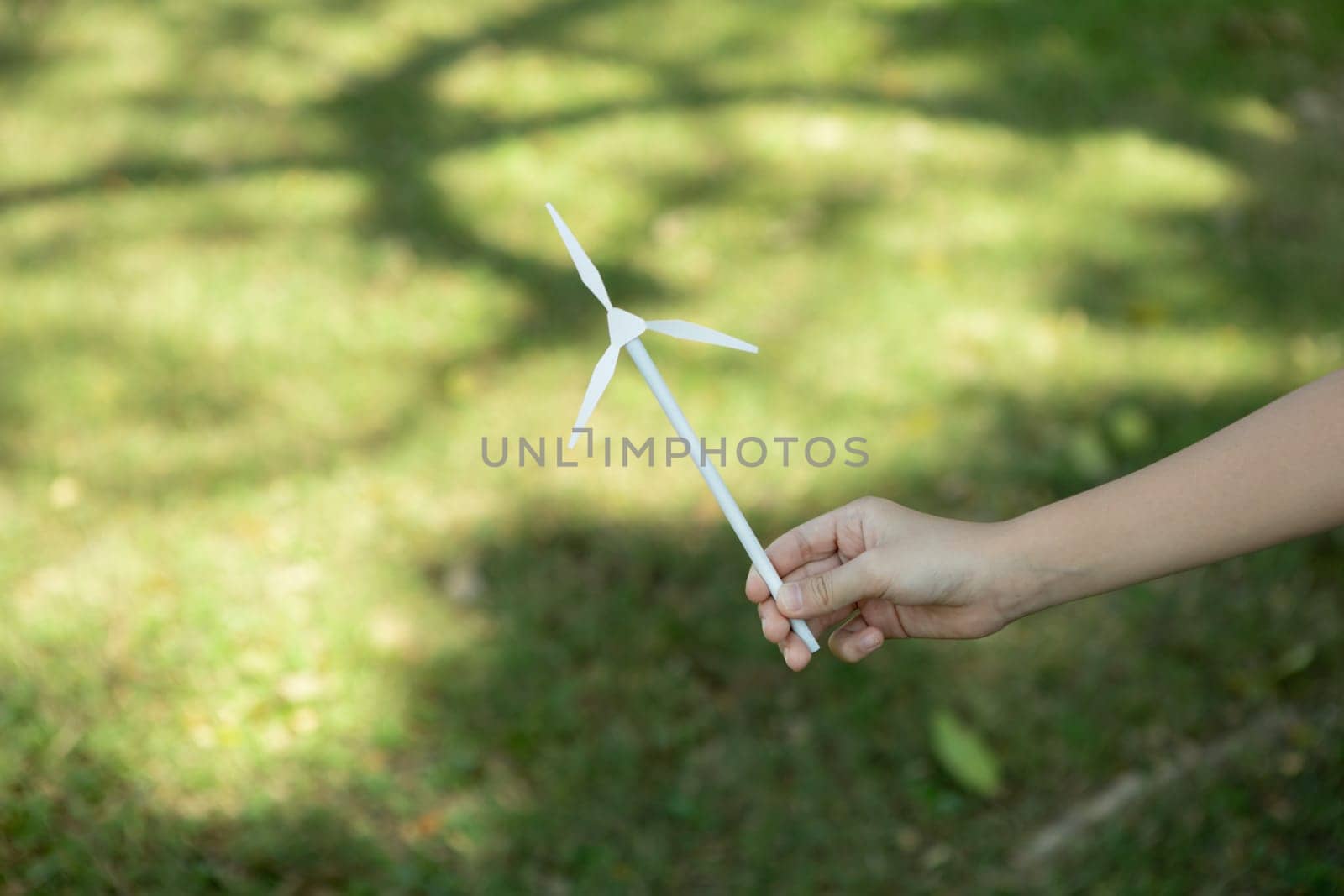 Little boy holding windmill or wind turbine mockup model to promote eco clean and renewable energy technology utilization for future generation and sustainable Earth. Gyre