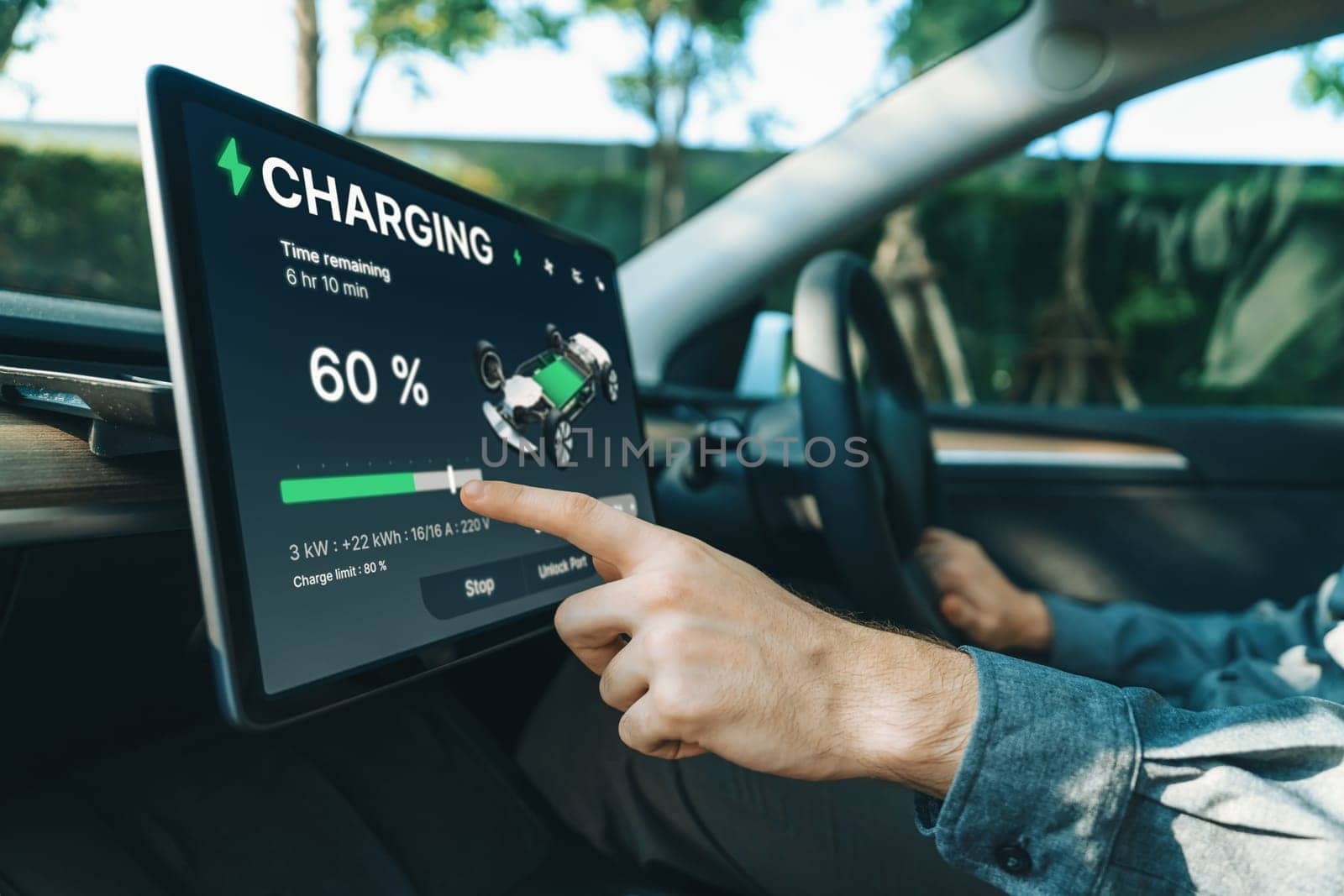 Electric car driver checks battery charging status, range and charging limit on app screen in the car. Smart technology device show EV car recharging data of electric storage in car battery innards.