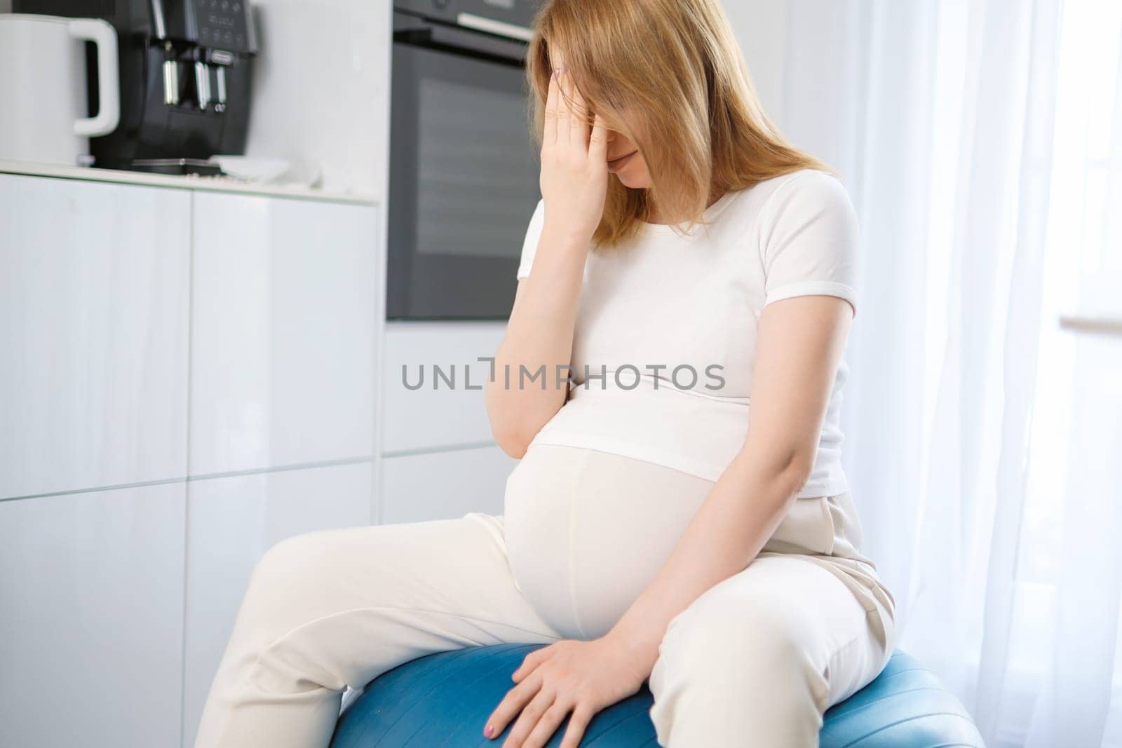 Headache during pregnancy. Pregnant woman sitting on the fit ball by vladimka